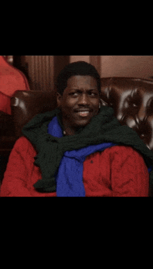 a man wearing a red sweater and a green sweater is sitting in a chair