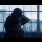 a man in a hooded jacket looks out a window