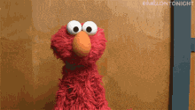elmo from sesame street standing in front of a door