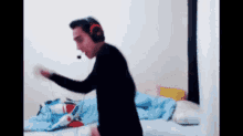 a man wearing headphones and a microphone is standing in a bedroom .