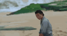 a man is sitting on a sandy beach looking at the ocean .