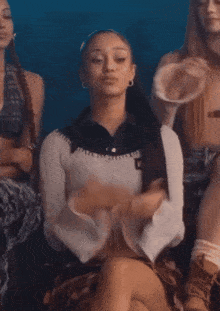 a woman wearing a crop top with kn on it sits with other women