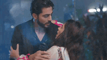 a man and a woman are standing next to each other in the rain and kissing .