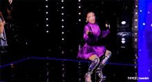 a woman in a purple dress and silver boots is laying on the floor on her stomach .