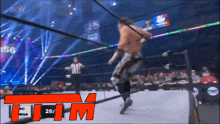 a wrestler is jumping over a rope while a referee watches .