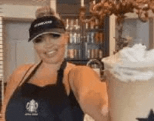 a woman is standing in front of a cup of coffee with whipped cream on top .