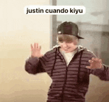 a young boy wearing a striped jacket and a hat is dancing .