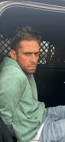 a man in a green puma hoodie is sitting in a car