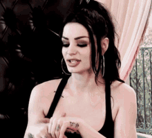 a woman with a tattoo on her wrist is wearing a black top .