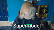 a man wearing a black shirt that says supermodel on it