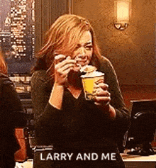 a woman is holding a cup of coffee and saying `` larry and me '' in a restaurant .