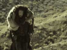 a man with a beard is carrying a large fur blanket on his back .