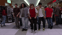 a group of people are dancing in a mall with a sign that says j.crew on it