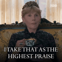 a woman is sitting on a couch holding a cup of tea and says i take that as the highest praise