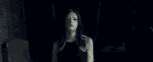 a woman in a black dress is dancing in the dark with her arms in the air .