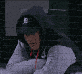 a man wearing a hoodie and a detroit hat