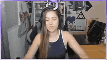 a woman wearing headphones and a tank top is sitting in front of a laptop computer .