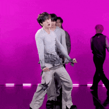 a group of young men are dancing on a stage with a pink background