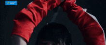 a woman in a red jacket is holding a sword with a blue u-front works logo in the corner