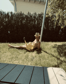 a man in a hat is laying in the grass holding a watering can