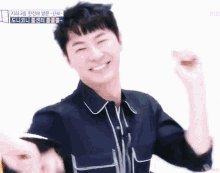 a man in a black shirt is smiling with his arms up
