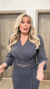 a woman in a blue dress with a gold belt has her hands out