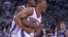 two basketball players are hugging each other while playing a game of basketball .