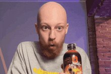 a bald man with a beard is holding a bottle of hot sauce that says ' aloha ' on it