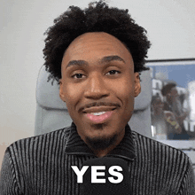 a man in a striped sweater is smiling with the word yes on his face