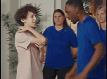 a group of people in blue shirts are standing in a room and talking to each other
