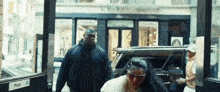 a woman wearing sunglasses is getting out of a car with a security guard behind her .