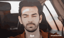 a man in a car with a bandage on his forehead is saying bye