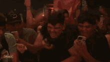 a group of young men are standing in a crowd with their hands in the air and their phones in their hands .