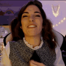 a woman is smiling while sitting in a chair in front of a purple wall .