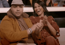 a man and a woman sit on a couch laughing