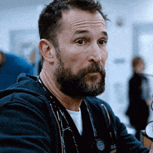 a man with a beard and a stethoscope around his neck has the letters rc on his shirt