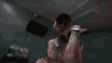 a man with a lot of tattoos on his body is drinking from a bottle .