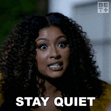 a woman with curly hair is saying to stay quiet