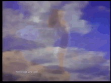 a woman in a white dress is standing on a rock in the ocean