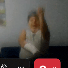 a blurred image of a man sitting on a couch with his hands in the air