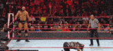 a referee is standing in a wrestling ring while a wrestler is kneeling on the ground .