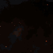 a close up of a fire with sparks flying in the dark