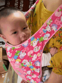 a baby in a pink hello kitty carrier