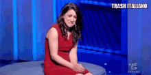 a woman in a red dress is crying while sitting on a blue couch .