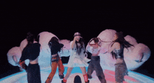 a group of women are dancing in front of a cloud in a dark room