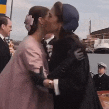 two women are kissing each other on the cheek in front of a crowd .
