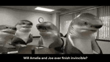 a group of sharks are sitting around a table in a conference room .