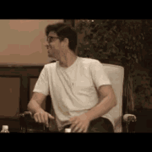 a man in a white shirt is sitting in a chair with his hands on his hips .