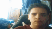 a young man is taking a selfie while sitting in a chair in a room .