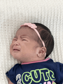 a baby wearing a headband and a shirt that says cute